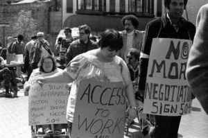 People holding signs which state "Access to Work" and "No More Negotiations, Sign 504"