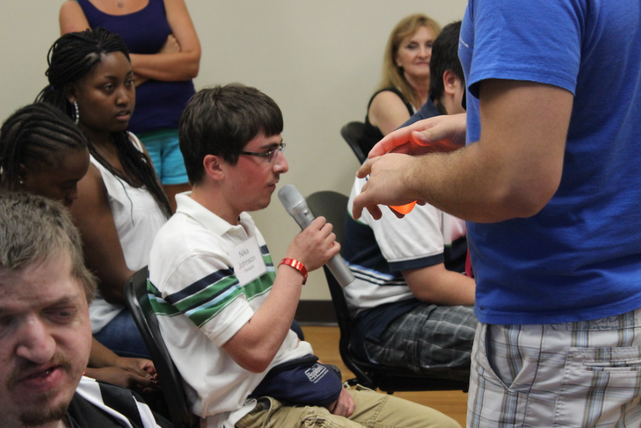 student speaks into a microphone at a community meeting