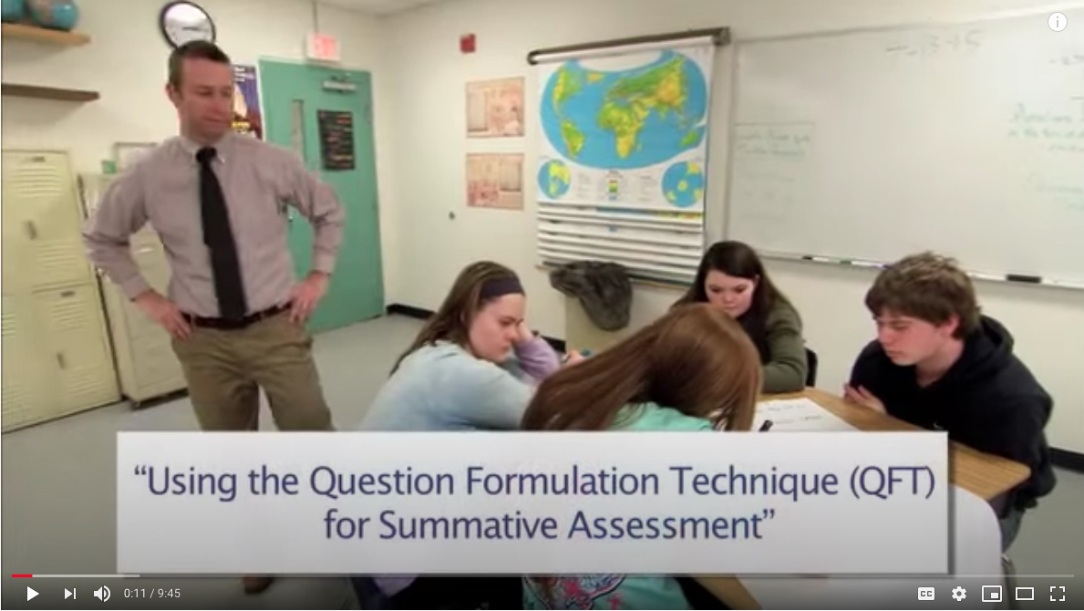 Teacher observes four students huddled over a primary source. 