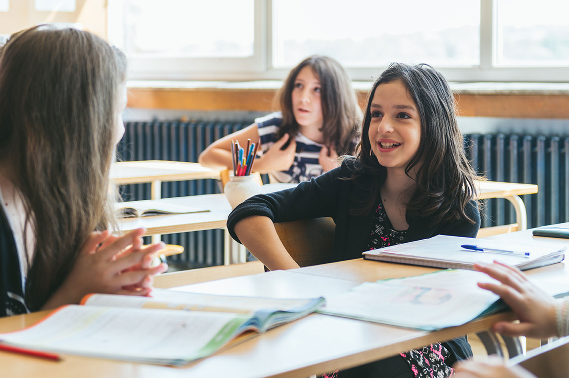 Elementary students at desks talking with each other