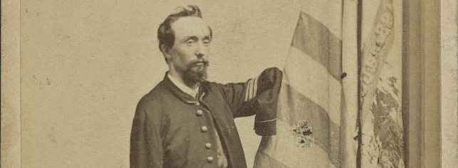 A white man with beard, wearing a Union Army jacket. His sleeves are empty.