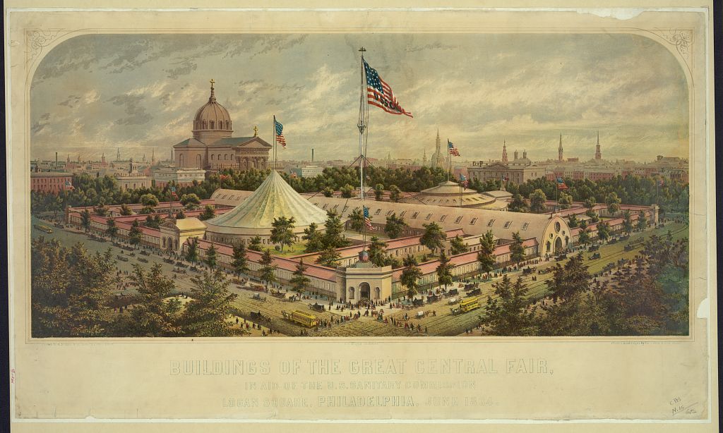 A print of a drawing of the fairgrounds for the Great Central Fair. The skyline of Philadelphia is in the background of the image. In the center, a large American flag flies over the fair buildings, including a central hall and a large white circular tent. People are lined up to enter the fair from the surrounding streets. 