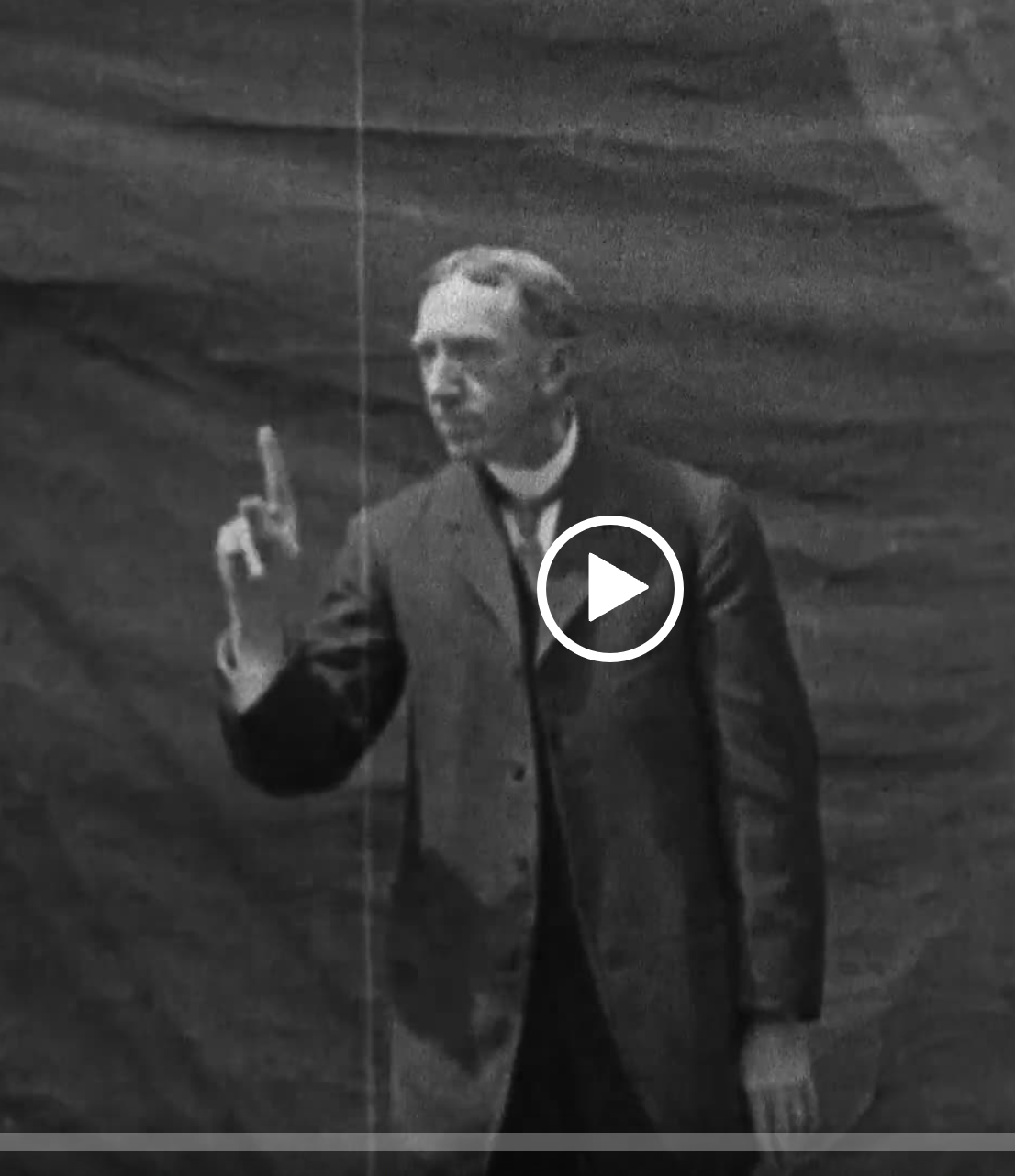 Screen cap from a film of George Veditz wearing a suit and giving a speech in American Sign Language. 