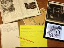 A desktop contains a textbook, ipad, historic map of immigration routes, and the Library of Congress analysis tool.
