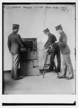 Three soldiers take a long paper feed from a wireless machine