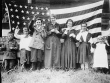 Seven deaf students stand in front of old U.S. flag as they sign the National Anthem