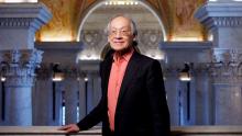 An older Asian American man stands in the elegant marbled hall of the Library of Congress.
