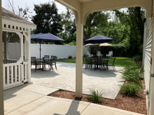 tables with umbrellas, chairs on grass under trees, screened patio next to building door