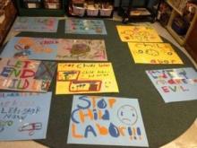 many student-made posters denouncing child labor are spread on a classroom table