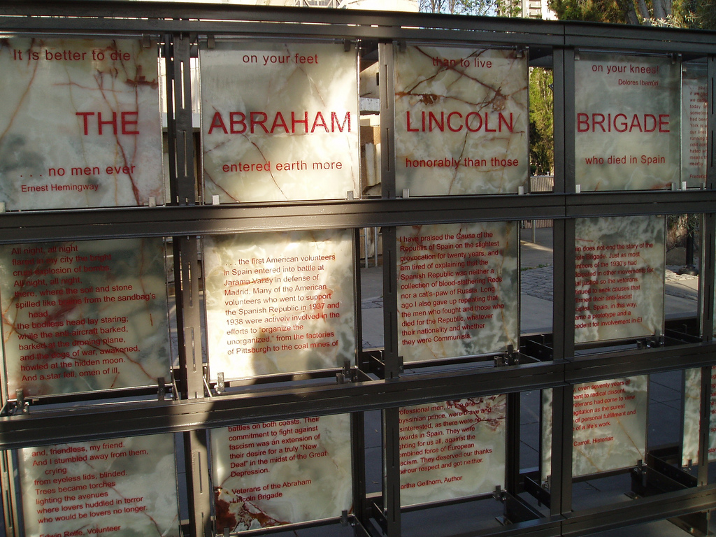 photo of large marble tiles (4 across, 3 rows) with red text. It is mounted outdoors upright in a frame. 