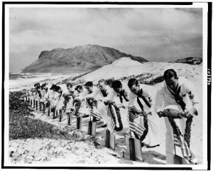 Seamen at Kaneohe Naval Air Station decorate the graves of their fellow sailors killed at Pearl Harbor, December 7, 1941 / Official U.S. Navy photograph.