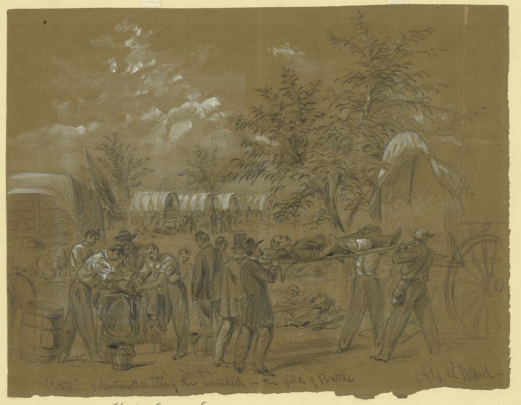 In this sketch, four men in civilian clothes and hats carry a soldier with a bandaged leg, perhaps toward a covered wagon which has a U.S. flag. Two surgeons in shirtsleeves are cutting off the leg of a soldier lying on a table table. One surgeon grips the man’s leg. The thigh bone and stump are clearly visible. The other leg dangles, still wearing a boot. There are buckets on the ground. Four other men also attend the operation, including one working on a shelf at the back of a medical wagon. Two men in un