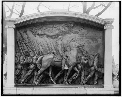 In this bronze sculpture, a white mounted officer rides beside a column of African American soldiers with guns. An angel floats above them.