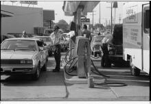 Several cars wait in line to get gas at a gas station.