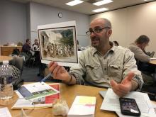 Teacher holds up a political cartoon primary source. 