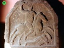 Stone with a man on a horse and a fallen man carved.