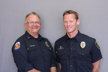 Two uniformed male white fire fighters pose, one shows an Arizona paramedic patch.