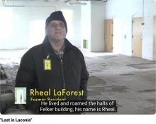 A white man wearing a stocking cap stands in a deserted dormitory with trash on the floor and battered walls and doors. A caption reads Rheal LaForest, Former Resident.