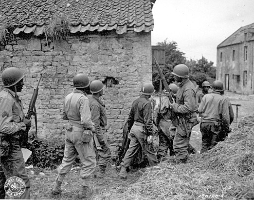 Photo of WWII African American soldiers with guns between destroyed builidings.